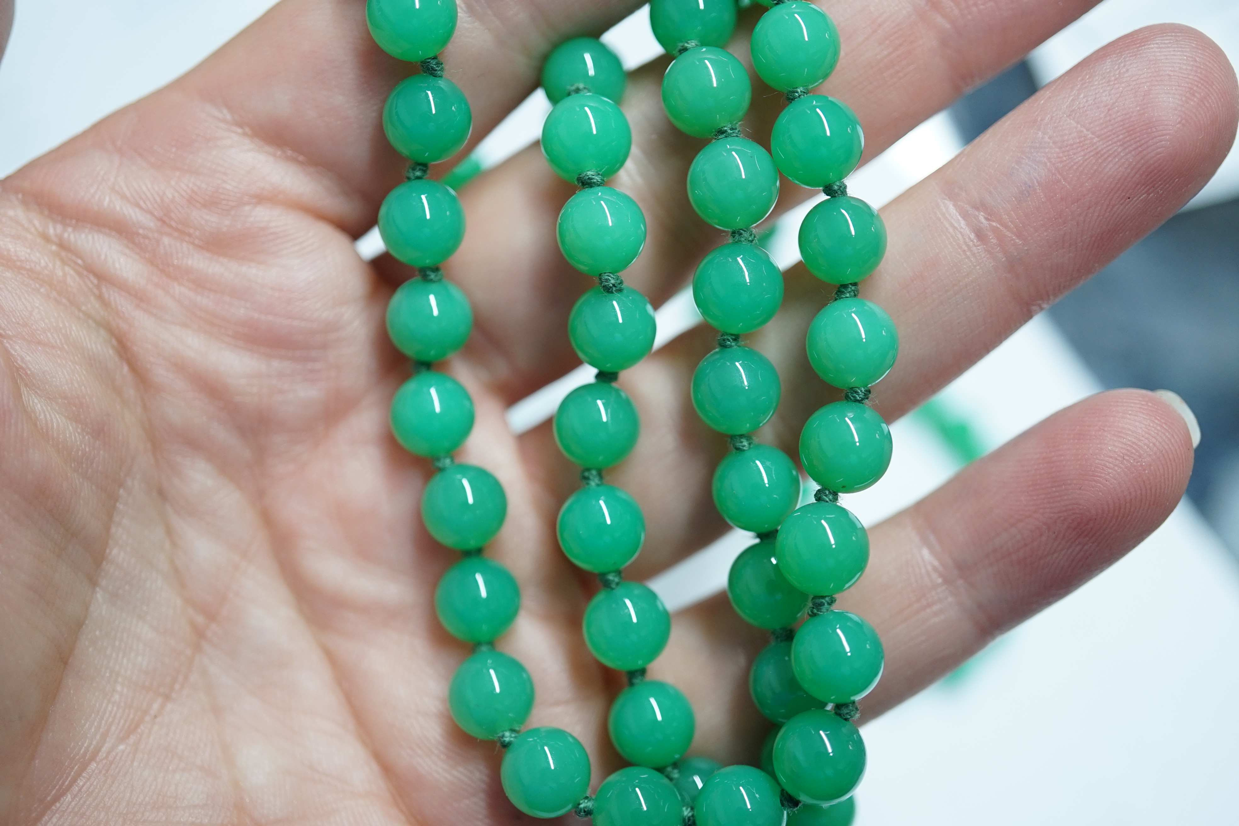 A modern long single strand jadeite bead necklace, with a cabochon jade and diamond chip cluster set 18k clasp